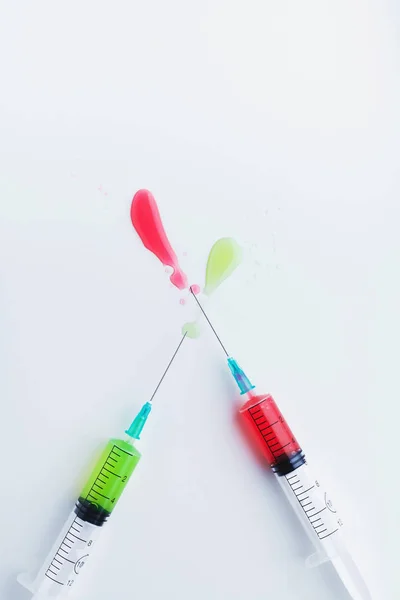 Two syringes filled with green and red liquids on white backgrou — Stok fotoğraf