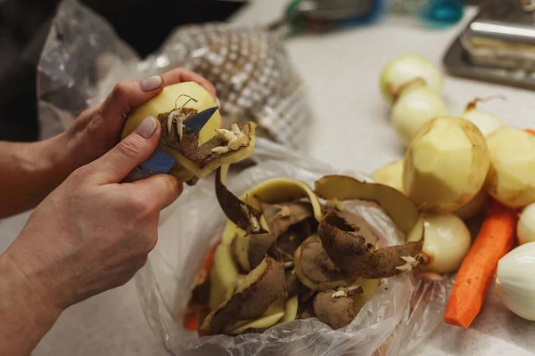 Elleri yıkanmamış patatesi küçük plastik poşetin üzerine soyuyordu.