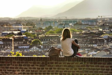 Kadın yalnız arkadan görünüm izlemek günbatımı Torino İtalya Mayıs 2016 yaklaşık terasında tuğla duvarına hill açısından şehir panoraması