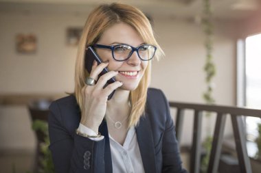 Cep telefonu üzerinde konuşurken bardaklarda neşeli genç güzel kadın