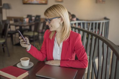 Genç sarışın kadın akıllı telefon, Kahve Dükkanı, iletide manifatura kullanarak Restoran