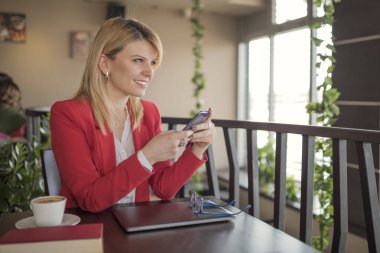 Akıllı telefon, kahve iletisinde manifatura kullanan genç sarışın kadın