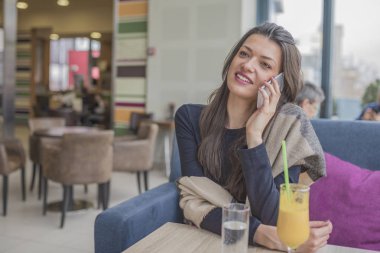 Güzel gülümseyen genç kadın kapalı oturan ve mafya üzerinde konuşuyor