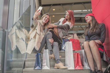 Üç genç ve güzel kız alışveriş torbaları ve g tutuyor