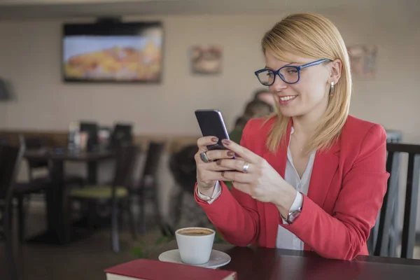 Akıllı telefon, kahve iletisinde manifatura kullanan genç sarışın kadın