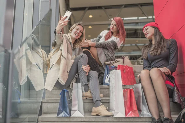 Üç genç ve güzel kız alışveriş torbaları ve g tutuyor