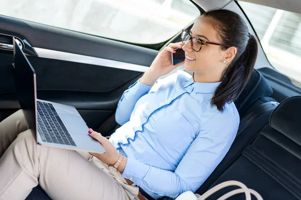 İş kadını arabada oturuyor ve cep telefonuyla konuşuyor. Arabadaki bir iş kadını telefonda konuşuyor. Arabadaki güzel iş kadını. İş ve yaşam tarzı konsepti..