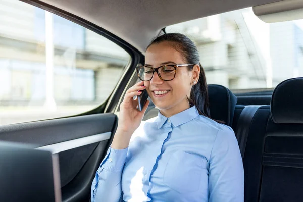 İş kadını arabada oturuyor ve cep telefonuyla konuşuyor. Arabadaki bir iş kadını telefonda konuşuyor. Arabadaki güzel iş kadını. İş ve yaşam tarzı konsepti..