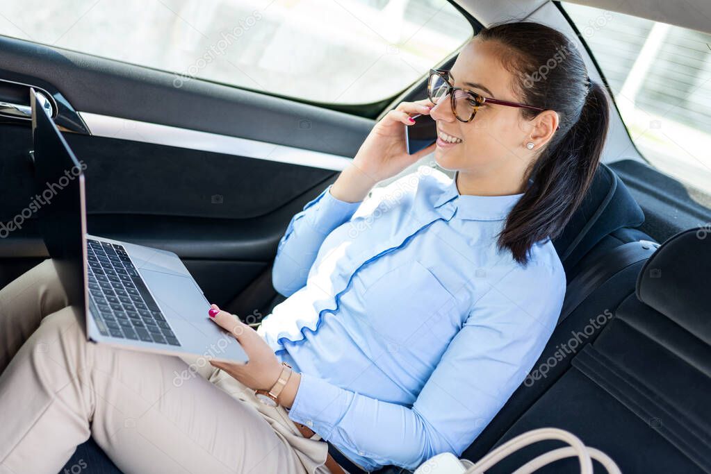 Business woman sitting in the car and talking on the cell. Businesswoman in a car on the phone. Beautiful business woman in the car.Business and lifestyle concept.