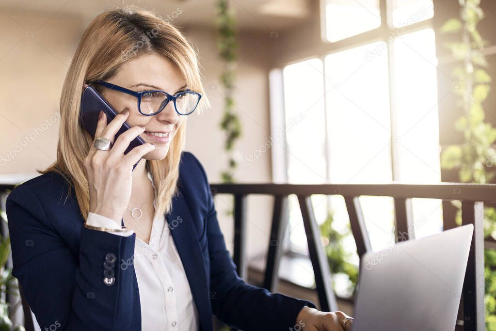 Business woman in cafe with business plan. Beautiful girl is working on laptop. Business and lifestyle concept.