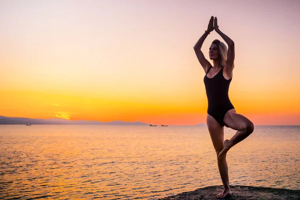 Şafakta plajda yoga yapan bir kız. Sağlıklı yaşam tarzı kavramı.