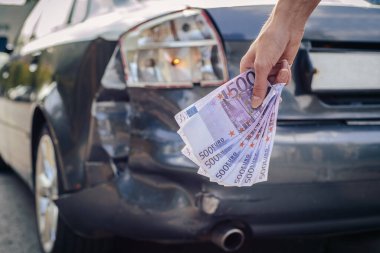Elinde bozuk bir arabanın arka planında 500 Euro 'luk banknot paketi vardı. Sigorta tazminatı kavramı.