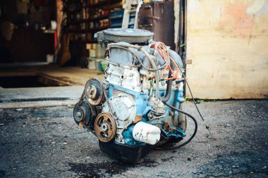 Arabadan çıkarılmış ve garajın yanında duran eski bir motorun yakın çekimi..