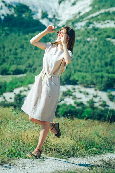 山岳地帯を歩くサングラスの魅力的な女の子は 晴れた日と良い気分を楽しんでいます — ストック写真