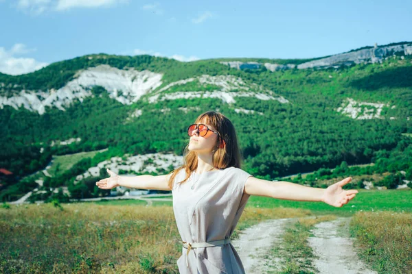 山岳地帯を歩くサングラスの魅力的な女の子は 晴れた日と良い気分を楽しんでいます — ストック写真