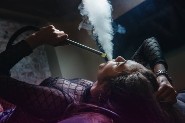 Kulüpte nargile içen genç ve güzel bir kız. Seksi kadın duman üfledi..