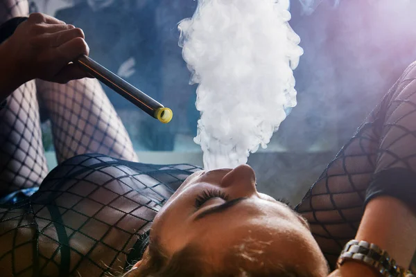 Kulüpte nargile içen genç ve güzel bir kız. Seksi kadın duman üfledi..