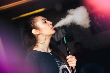 Kulüpte nargile içen genç ve güzel bir kız. Seksi kadın duman üfledi..