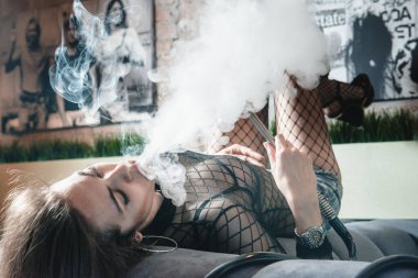 Kulüpte nargile içen genç ve güzel bir kız. Seksi kadın duman üfledi..