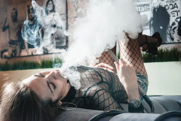 Kulüpte nargile içen genç ve güzel bir kız. Seksi kadın duman üfledi..