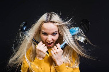 Dağınık saçlı genç bir kız mutfak aletleri tutuyor ve hiçbir şey pişiremeyeceği korkusuyla buraya geliyor. Genç ev hanımı konsepti.