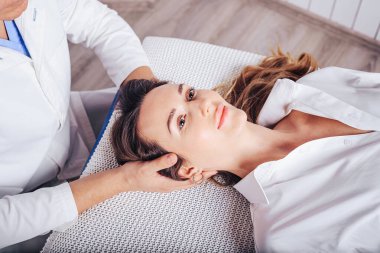 Bir osteopat ile doktor randevusunda olan genç bir kız, boyun bölümlerinin omurgasının eğimini tedavi ediyor..