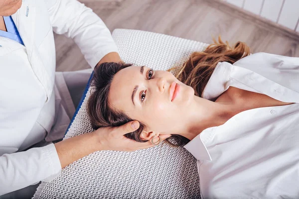 Bir osteopat ile doktor randevusunda olan genç bir kız, boyun bölümlerinin omurgasının eğimini tedavi ediyor..