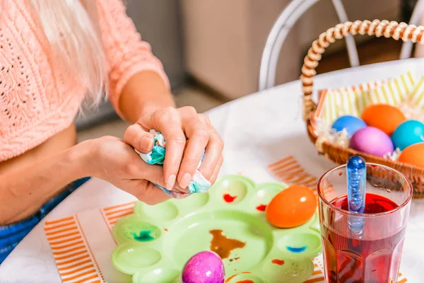 Happy Easter. A woman paints Easter eggs, make a surprise for the family on holiday.