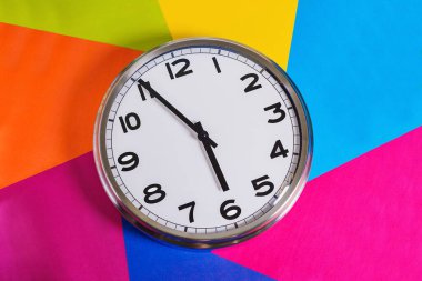 Çelik saat çok renkli bir arka planda, eller altıya beş var. Kapatın. Yukarıdan görünüşü. 