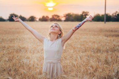 Genç bir kız Olgun bir buğday tarlasında yürüyor