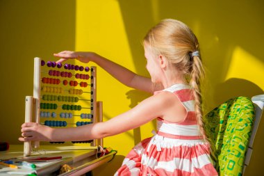 Evdeki küçük bir kız matematik okurken faturalarla ödev yapıyor.