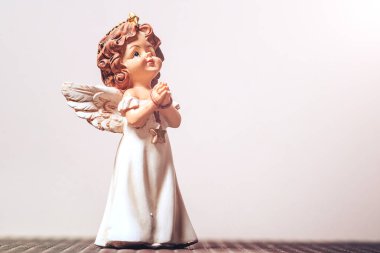 Bir koruyucu meleğin küçük seramik figürü dua ederken ellerini birbirine kenetliyor. yakın plan, kopyala.