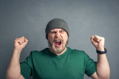 Kaldırılmış elleri ve sıkılmış yumrukları olan ve evet diye bağıran sakallı bir adamın portresi. Şans, liderlik ve zafer kavramı..