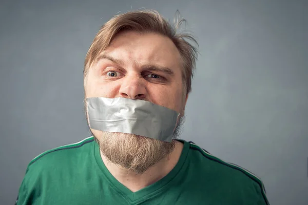 A bearded man with duct tape over his mouth. The concept of censorship.