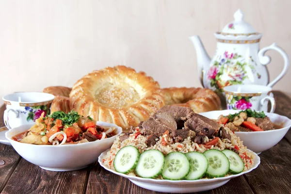 A table with traditional oriental dishes - lagman, shurpa, pilaf and tortillas — Stock Image A table with traditional oriental dishes - lagman, shurpa, pilaf and tortillas Stock Picture