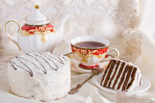 Cake with coconut sprinkling and a cup of black tea — Stock Photo, Image