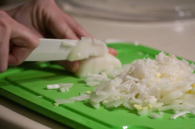 Yeşil kesme tahtası üzerinde seramik bıçak ile kesme soğan