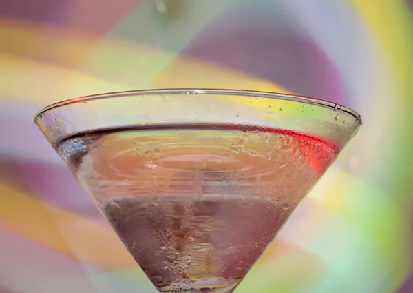 A martini glass with a cocktail in beautiful light of different colors