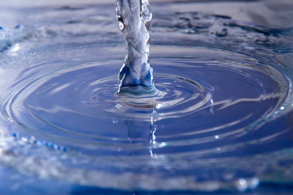 Spray and waves from water falling on a flat transparent surface