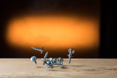 Tahta bir arka planda kontrplak üzerine düşen kendi kendine dokunan vidalar, siyah, krom ve sarı