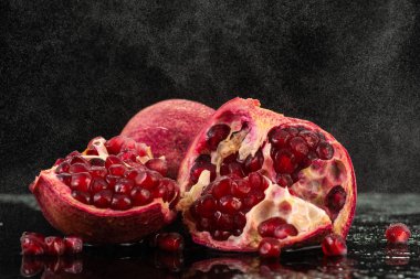 kırmızı nar meyvesi, akıntılı ve siyah arkaplanda biraz su.