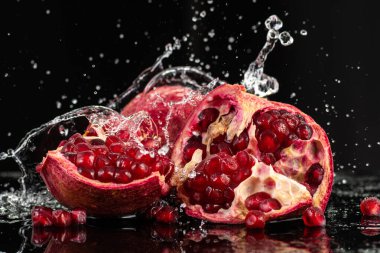 kırmızı nar meyvesi, akıntılı ve siyah arkaplanda biraz su.