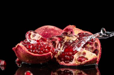 kırmızı nar meyvesi, akıntılı ve siyah arkaplanda biraz su.