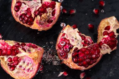 kırmızı nar meyvesi, akıntılı ve siyah arkaplanda biraz su.