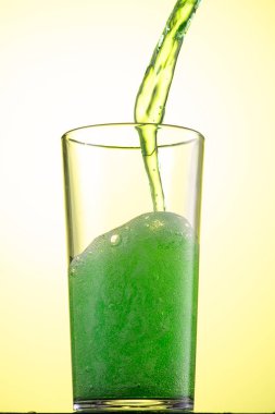 Sarı ya da yeşil karbonatlı limonata. Bardakta buz, akış ve sıçrama var.