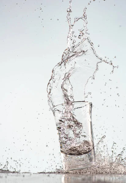 splash of pure water in a glass on a blue background