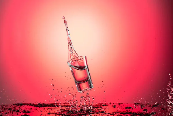 Splash Flying Wineglass Water Vodka Red Gradient Background — стоковое фото