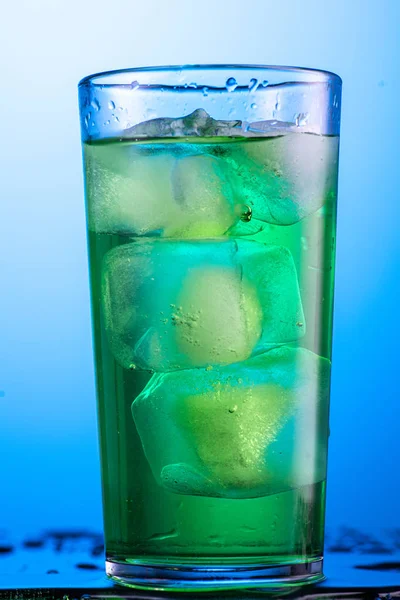 在装有冰块 水和水花的杯子中加入黄色或绿色碳酸柠檬水 — 图库照片