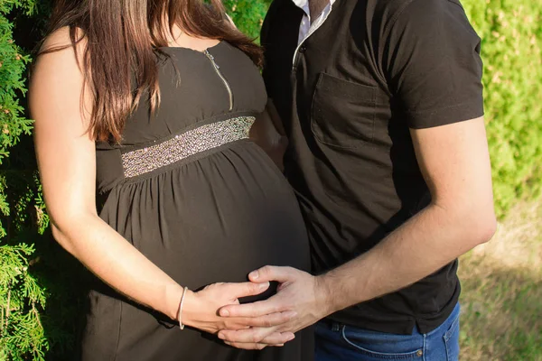 Ouple in afwachting van een baby die hand in hand op een zwangere tu — Stockfoto