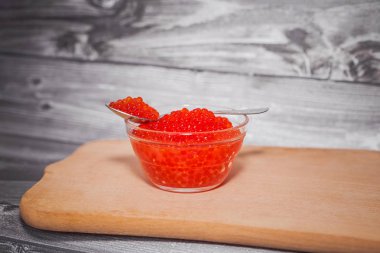 Ahşap oyun tahtası saydam bir tabak içinde kırmızı havyar 